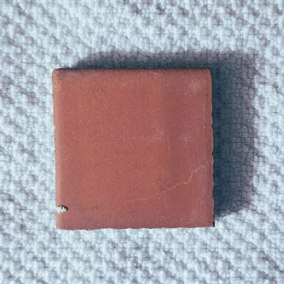 small square terracotta tile on textured cloth