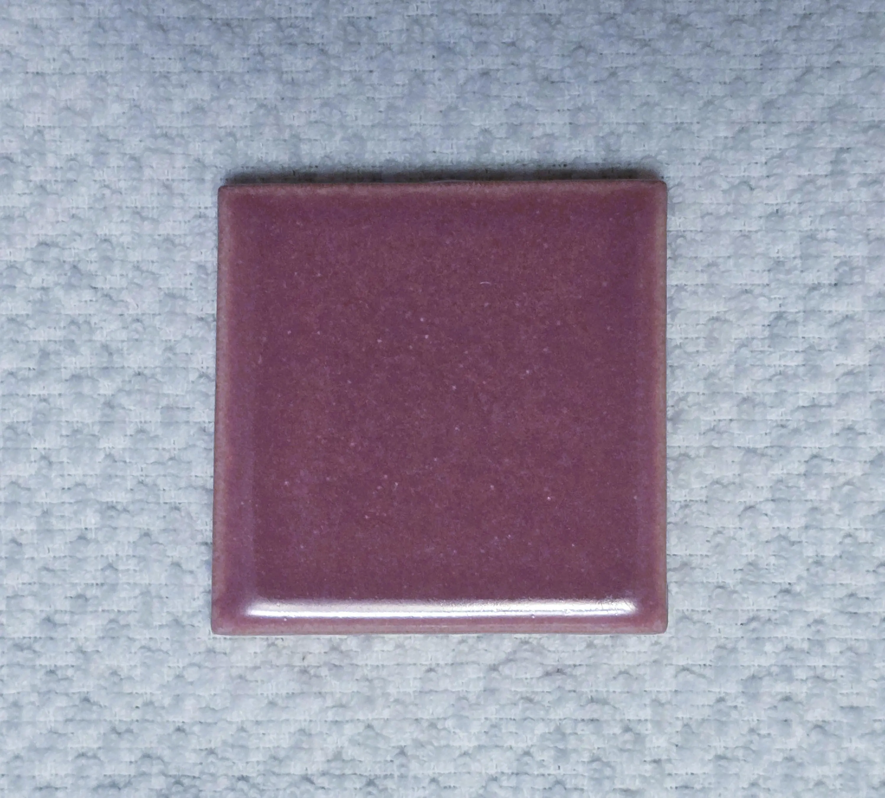 Purple square tile on textured surface.
