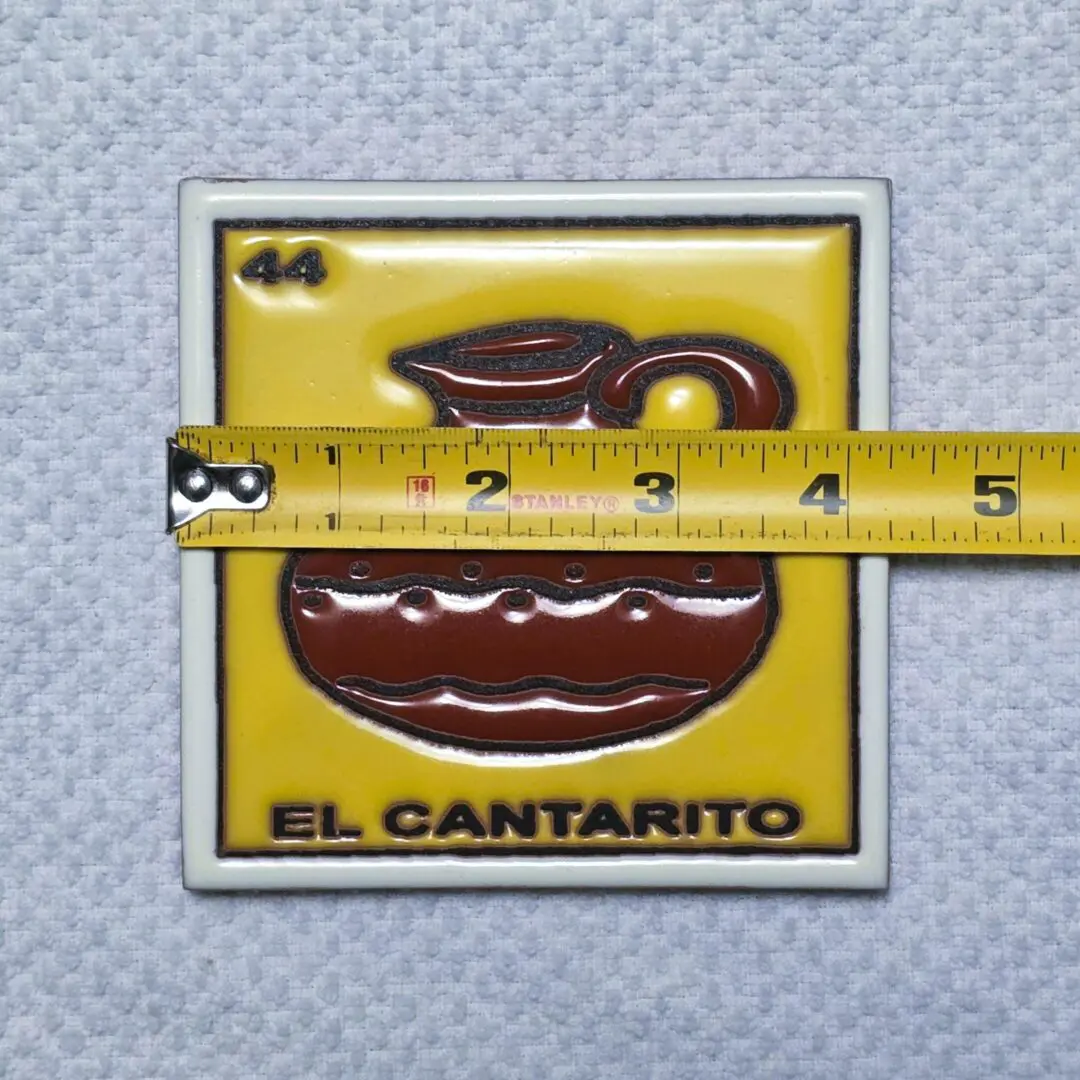 Tile with pitcher design and measuring tape.