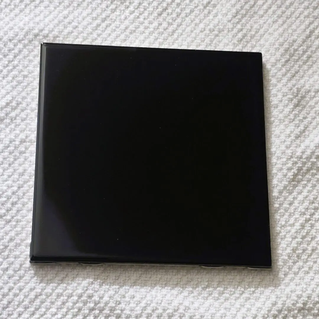 Glossy black square tile on textured white towel