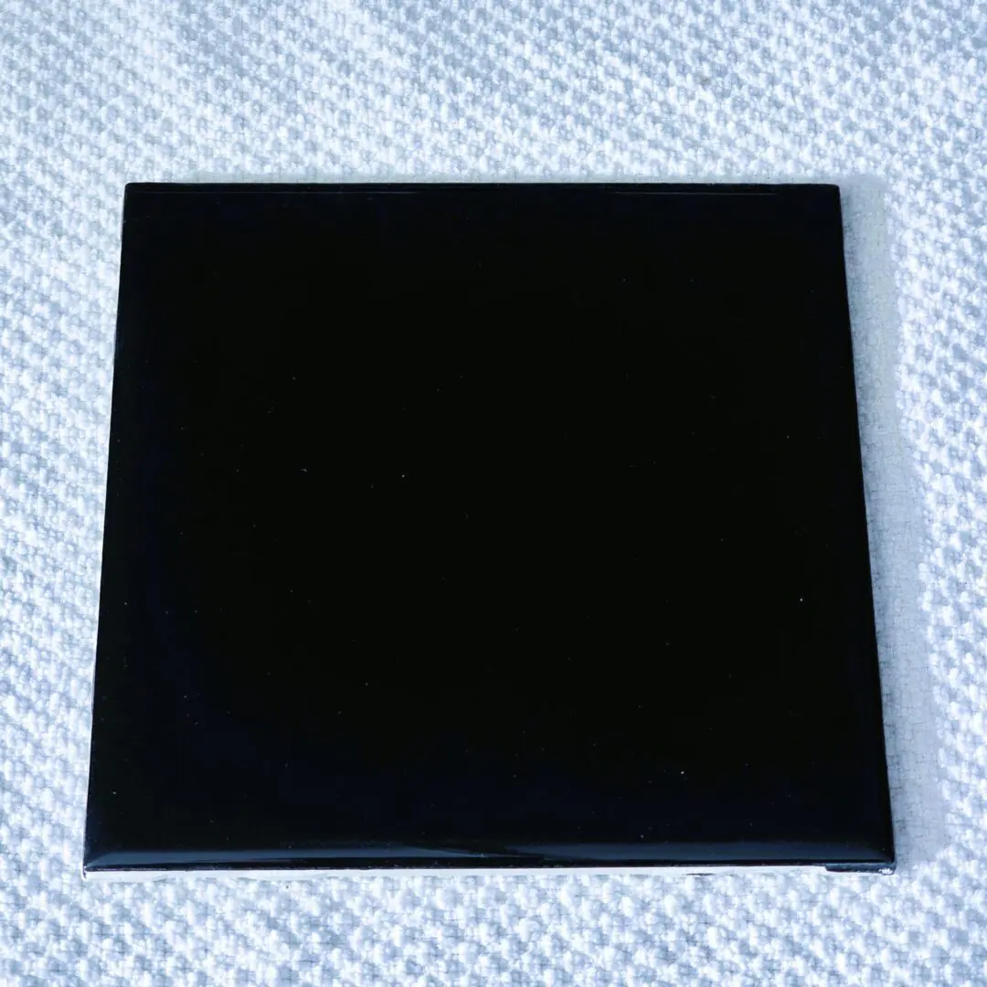 Glossy black square tile on textured cloth