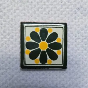 Decorative tile with a black and yellow flower design.