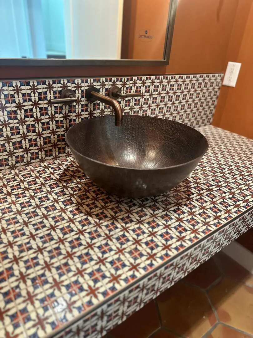Black metal bowl on a patterned countertop near a brown wall.